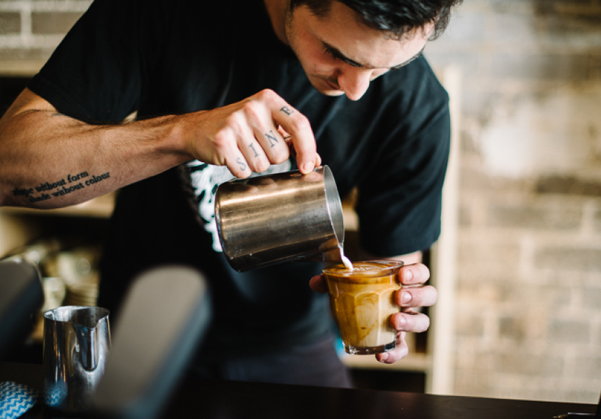 A barista pours a coffee into a glass