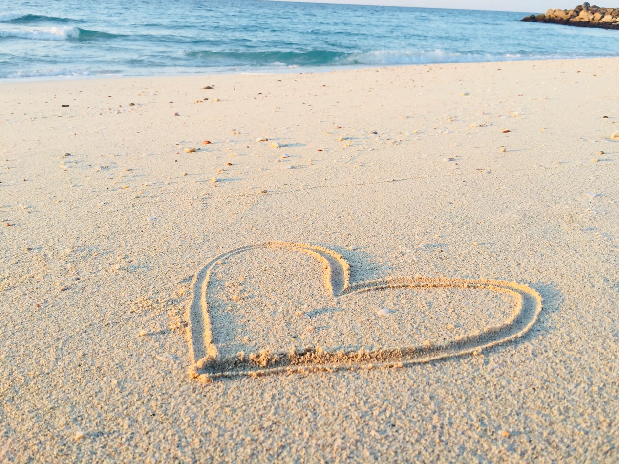 A heart is drawn into the sand at the beach