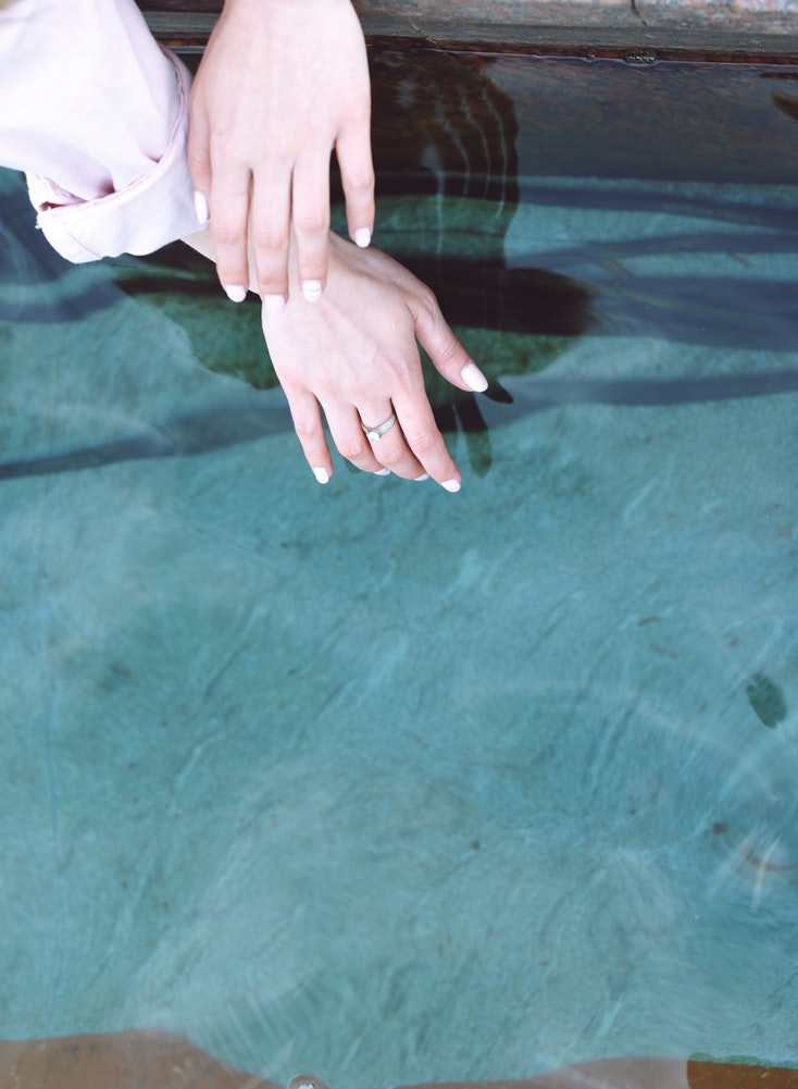 A woman dipping her hands in crystal clear blue water