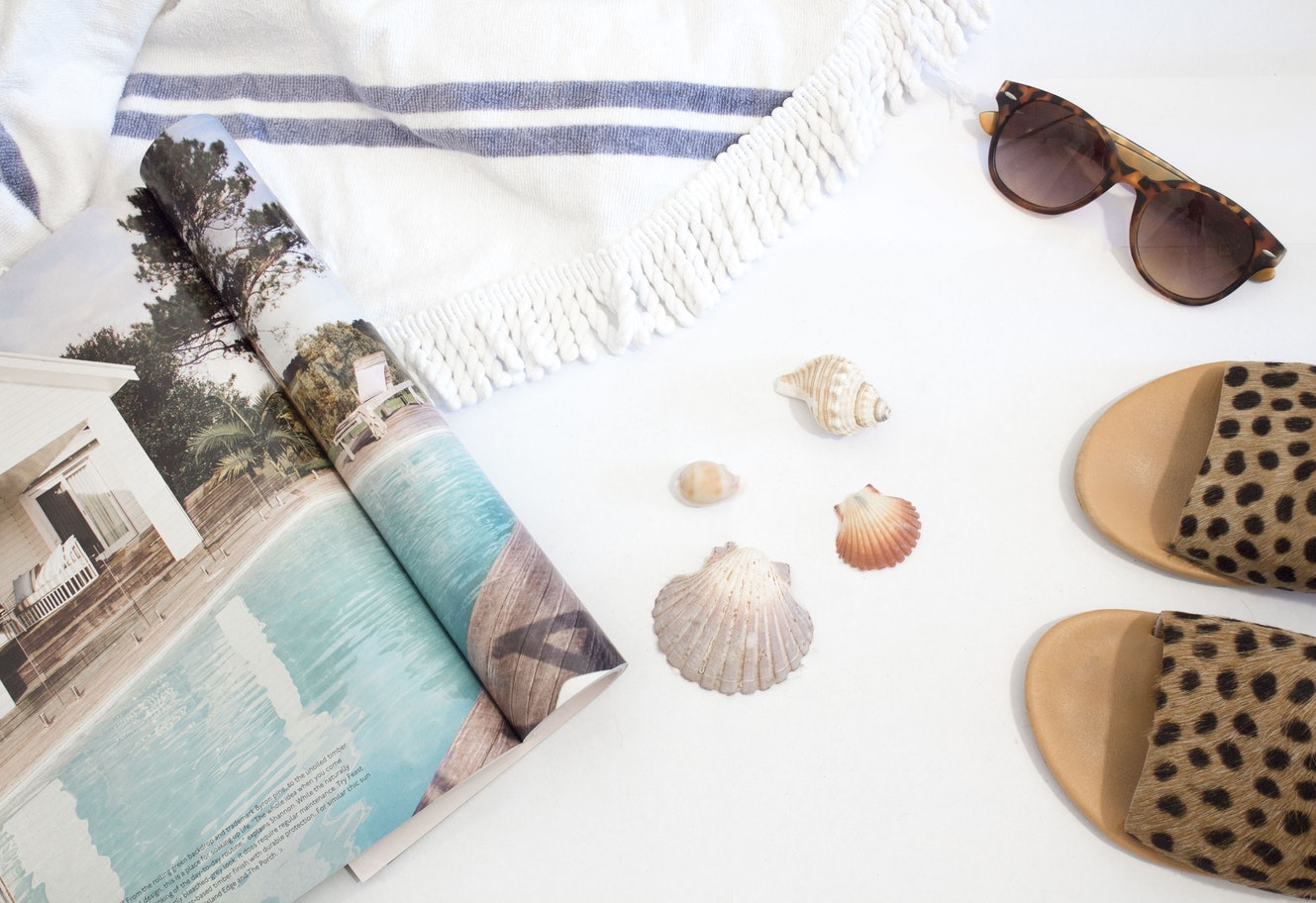 Beach essentials including a towel, sunglasses and magazine