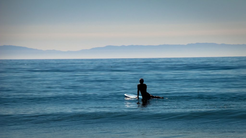 A solo surfer waits for a wave in the ocean