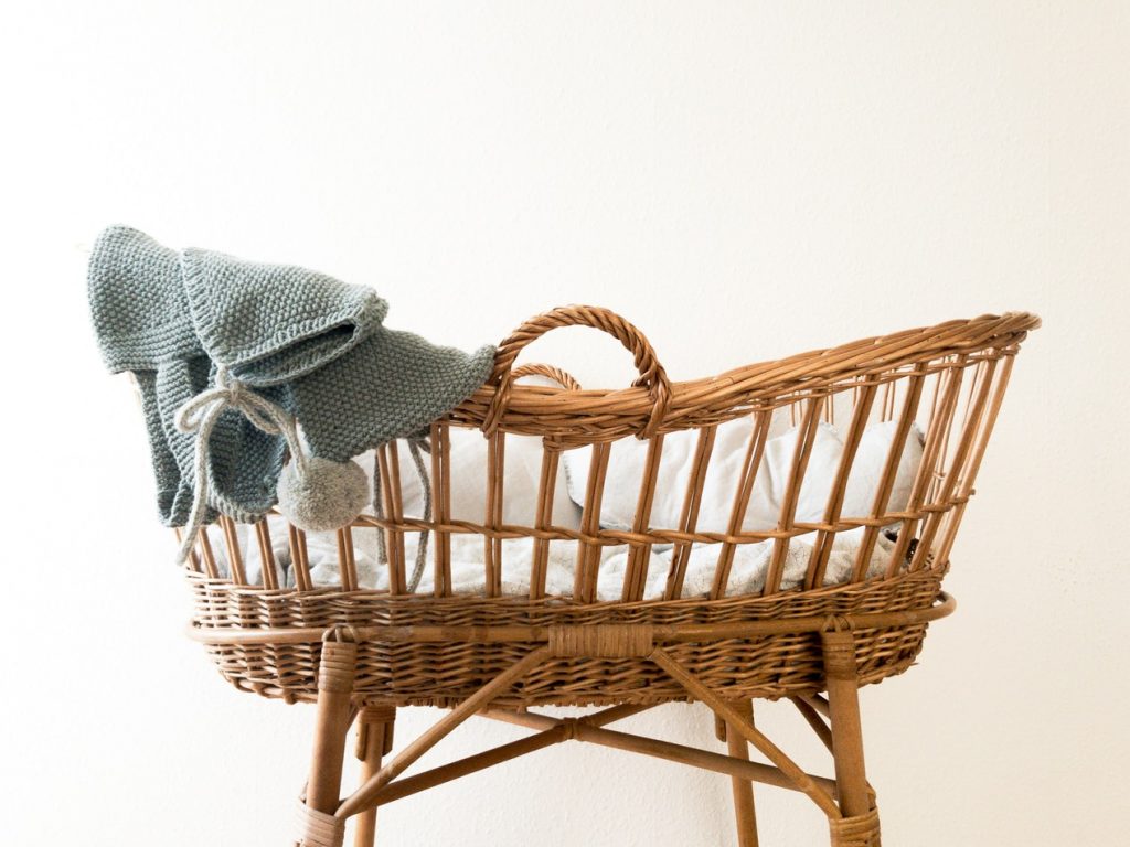 A baby crib with woollen throw rug draped over the side