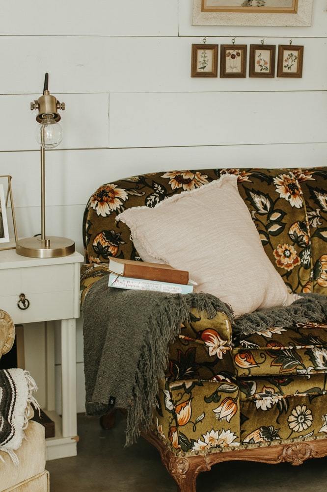 A floral couch with throw rug, comfortable cushion and books