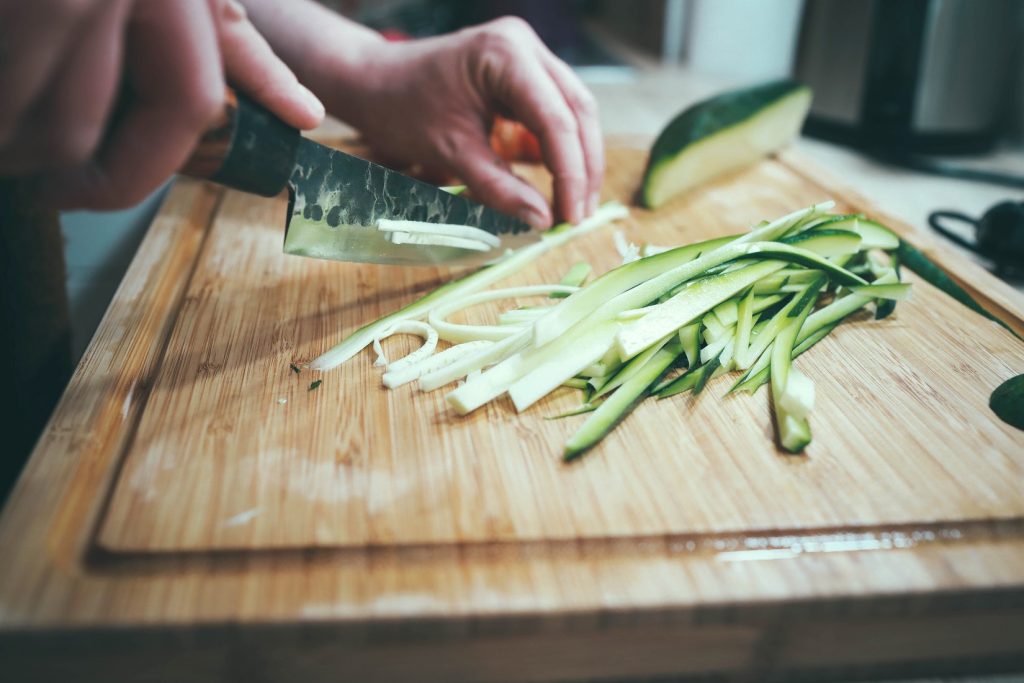 A person is chopping up zucchini