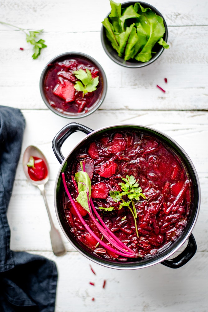 Bright red borscht soup in a bowl on a bench