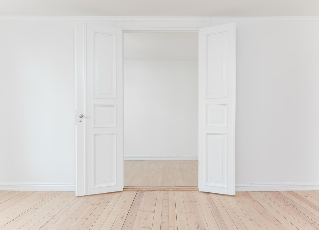 A white door is opening to an empty room