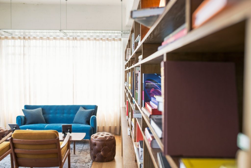 A therapist's room with a blue couch and wall of books