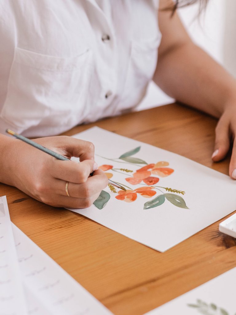 An artist sketches a commissioned piece of floral artwork.