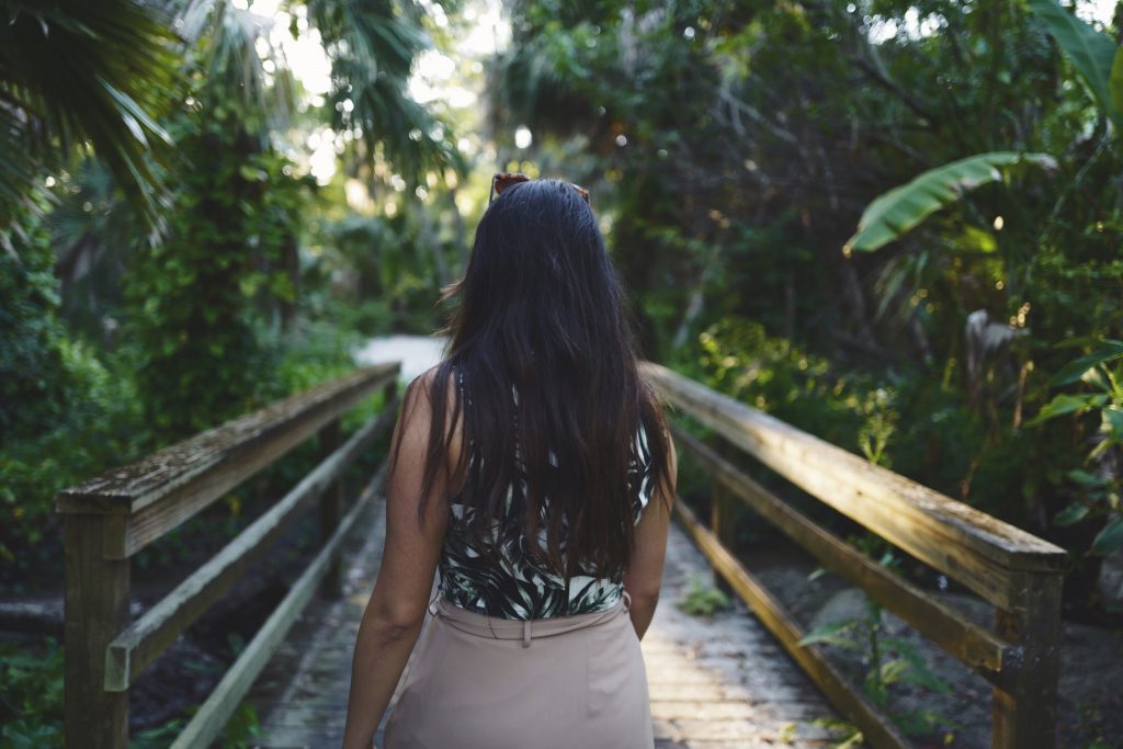 A woman walks along a bridge surrounded by lush rainforest