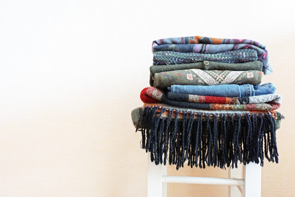 A stack of knitted scarves sits on a white chair