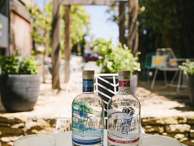 Two bottles of gin sit on a table in the lush outdoor garden