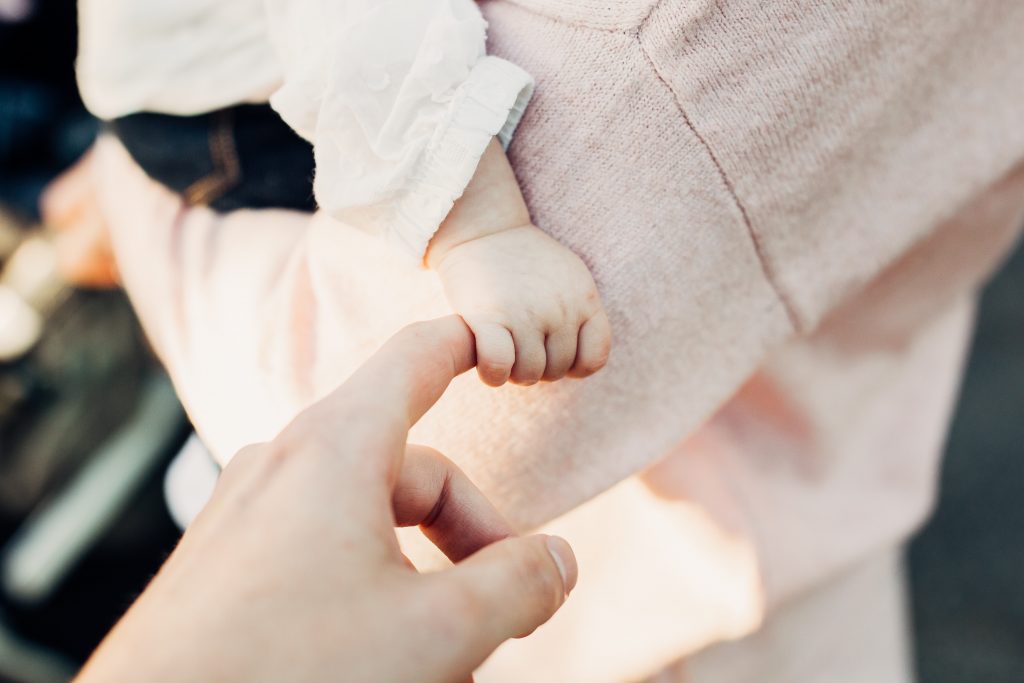 A baby wraps its fingers around its father's finger