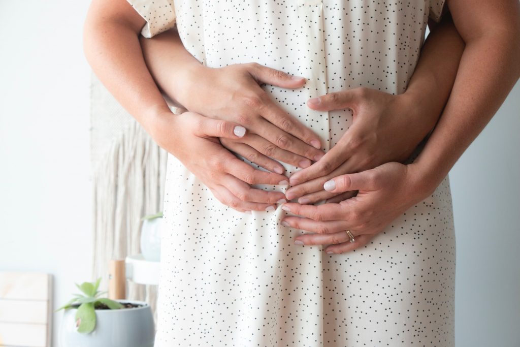 Parent's hands cradle a woman's pregnant belly