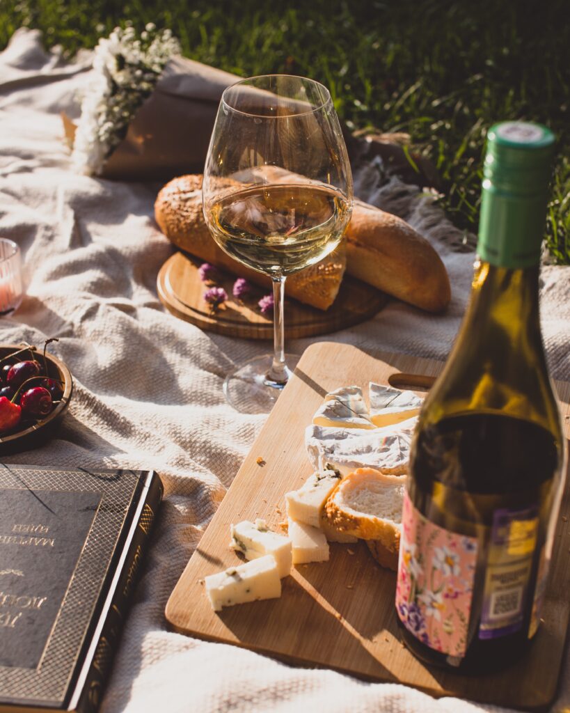 A picnic spread with white wine, cheese and bread