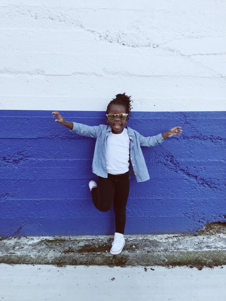 A child in sunglasses against a blue wall