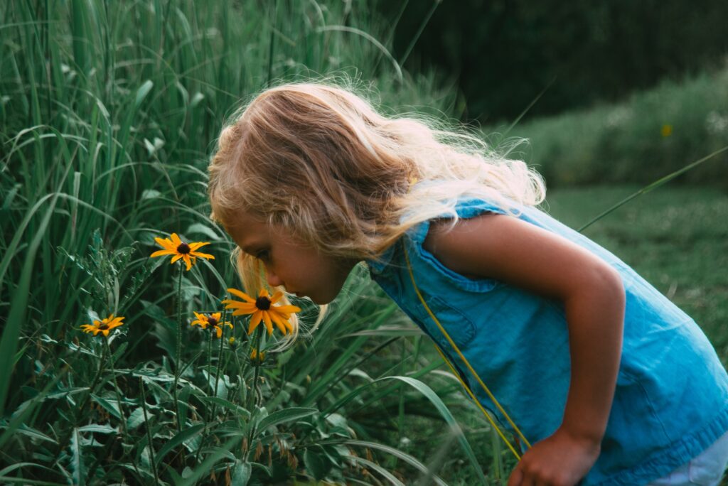 A girl sniffs yellow flowers